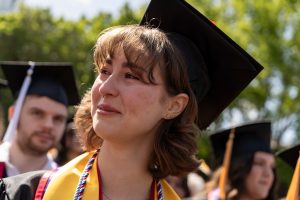 A student dressed in graduation cap and gown smiles during the 2024 Linfield University Commencement.
