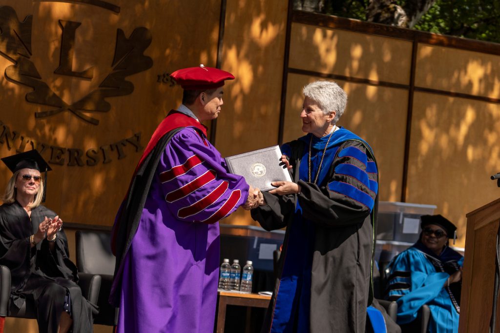 President Becky Johnson hands Shawn Chen an honorary doctorate speaks during the 2024 Linfield University Commencement.