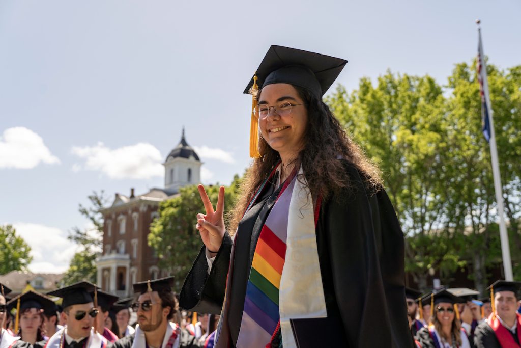 A student dressed in graduation cap and gown smiles during the 2024 Linfield University Commencement.