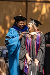 A student dressed in graduation cap and gown smiles during the 2024 Linfield University Commencement.