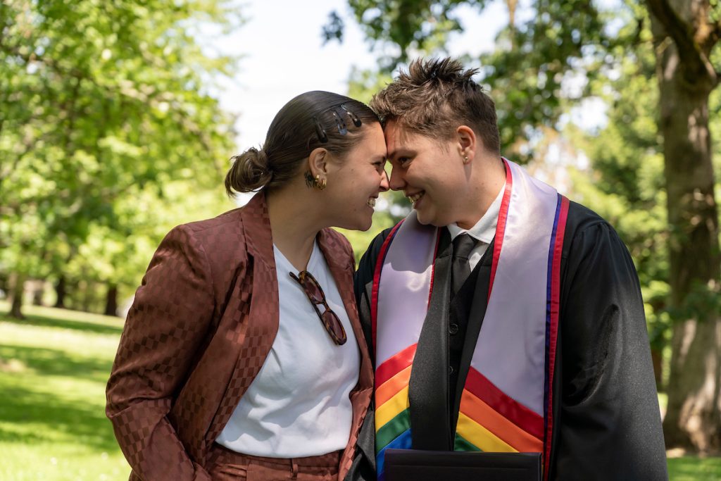 A student poses with their loved ones and smiles during the 2024 Linfield University Commencement.