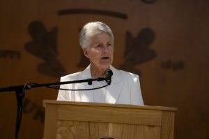 President Becky Johnson speaks at a podium with an oak backdrop that says ‘Linfield University' during the Linfield University 2024 Nursing Pinning Ceremony.