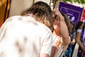 A family member places a purple stole with a red border around the neck of a Linfield University School of Nursing graduate.