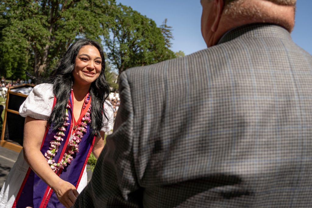 A nursing graduate smiles at Dean Paul Smith.