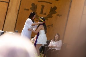 A family member places a purple stole with a red border around the neck of a Linfield University School of Nursing graduate.