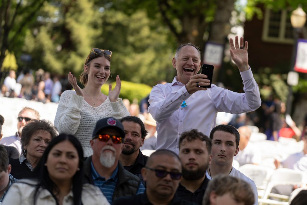 A family stands and cheers for their graduate during the Linfield University School of Nursing pinning ceremony.
