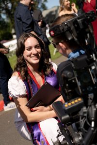 A family member places a purple stole with a red border around the neck of a Linfield University School of Nursing graduate.