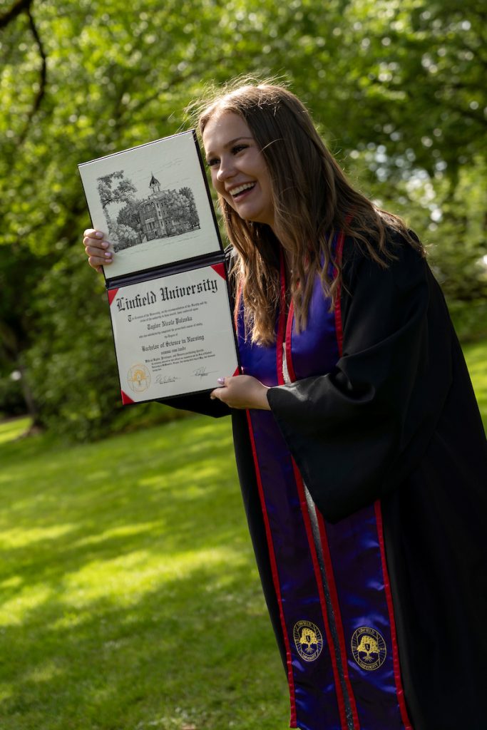 A Linfield University School of Nursing graduate shows off their diploma.