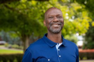 Damian Williams smiles as he stands in front of the Oak Grove on Linfield's McMinnville campus