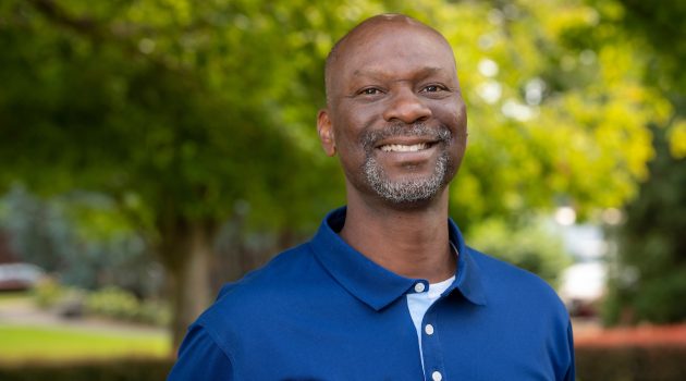 Damian Williams smiles as he stands in front of the Oak Grove on Linfield's McMinnville campus