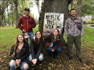 Students pose in front of an oak tree with a Linfield University Majestic Tree Week banner.