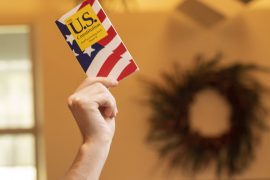 A hand holds a copy of the United States Constitution