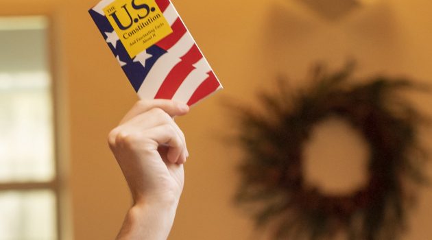 A hand holds a copy of the United States Constitution