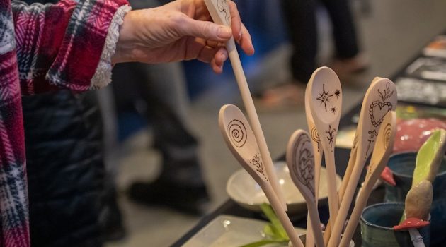 Multiple hand-carved wooden spoons and pottery at the student art market