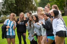 A group of first-year students smile and hold acorns from the Acorn Ceremony during Convocation. 