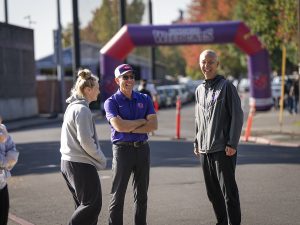 Three people talk and laugh during Linfield Homecoming 2024