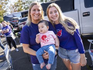 Two people and a baby pose for a photo during Linfield Homecoming 2024