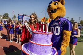 Mack the Wildcat holding the 100-year anniversary birthday cake during Linfield Homecoming 2024