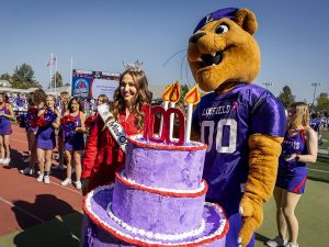Mack the Wildcat holding the 100-year anniversary birthday cake during Linfield Homecoming 2024