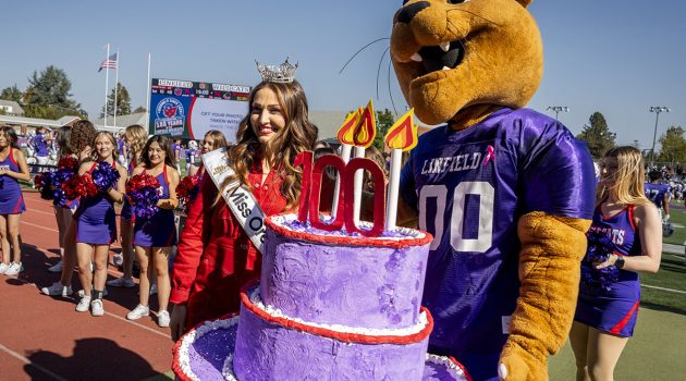 Mack the Wildcat holding the 100-year anniversary birthday cake during Linfield Homecoming 2024