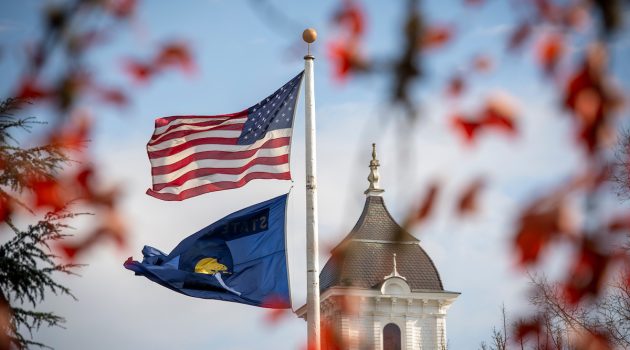 The Oregon and American flag wave in front of Pioneer Hall