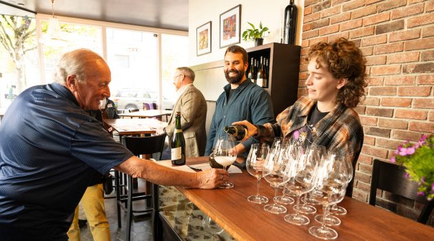 Guest get wine poured in a glass while manager Paul Johnson looks on.
