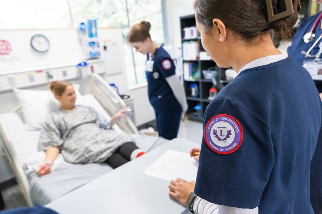 Linfield nursing students assist a patient in bed