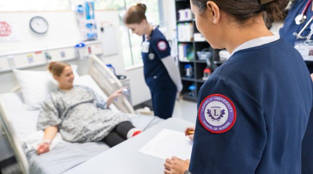 Linfield nursing students assist a patient in bed