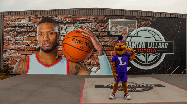 Mack the Wildcat poses on a basketball court at Damian Lillard Toyota with a mural behind him