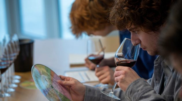 students smell wine in a glass while looking at flavor wheel