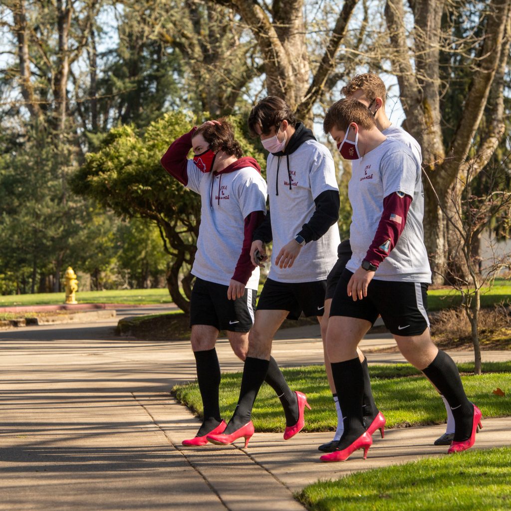 brothers of Pi Kappa Alpha walk in white shirts and red heels at charity event