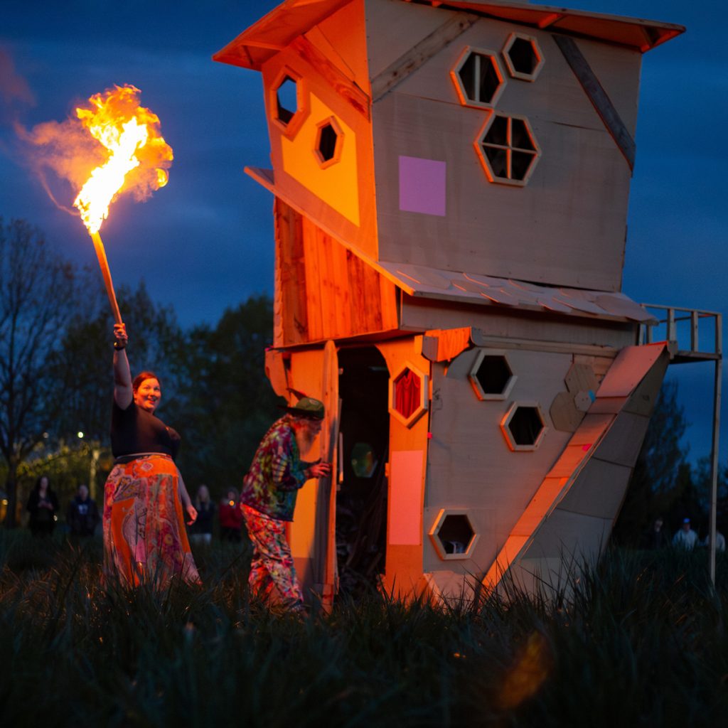 woman raises torch over head about to light structure on fire