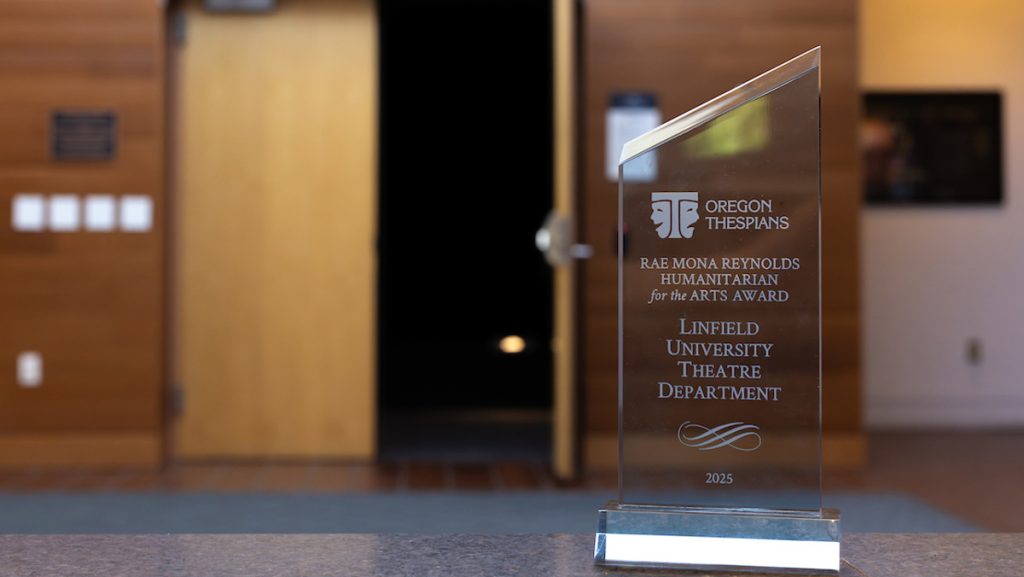 Close up of glass award that reads: Oregon Thespians. Rae Mona Reynolds Humanitarian for the Arts Award. Linfield University Theatre Department. 2025.