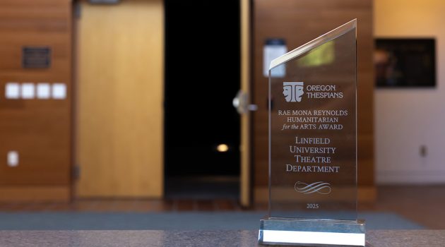 Close up of glass award that reads: Oregon Thespians. Rae Mona Reynolds Humanitarian for the Arts Award. Linfield University Theatre Department. 2025.