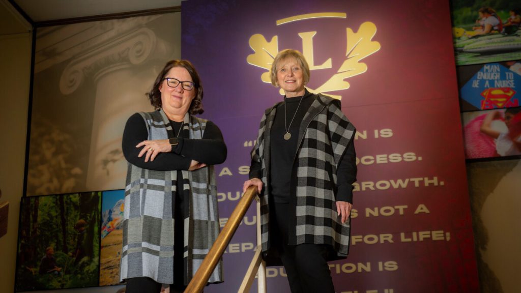 Associate deans Denise Farag '88 (left) and Virlena Crosley '89 (right) stand in front of mural inside Melrose Hall.