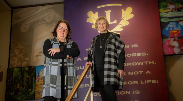 Denise Farag and Virlena Crosley stand in front of a Linfield display