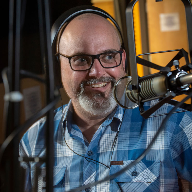 Kevin Curry in a podcast studio with mic in front of him