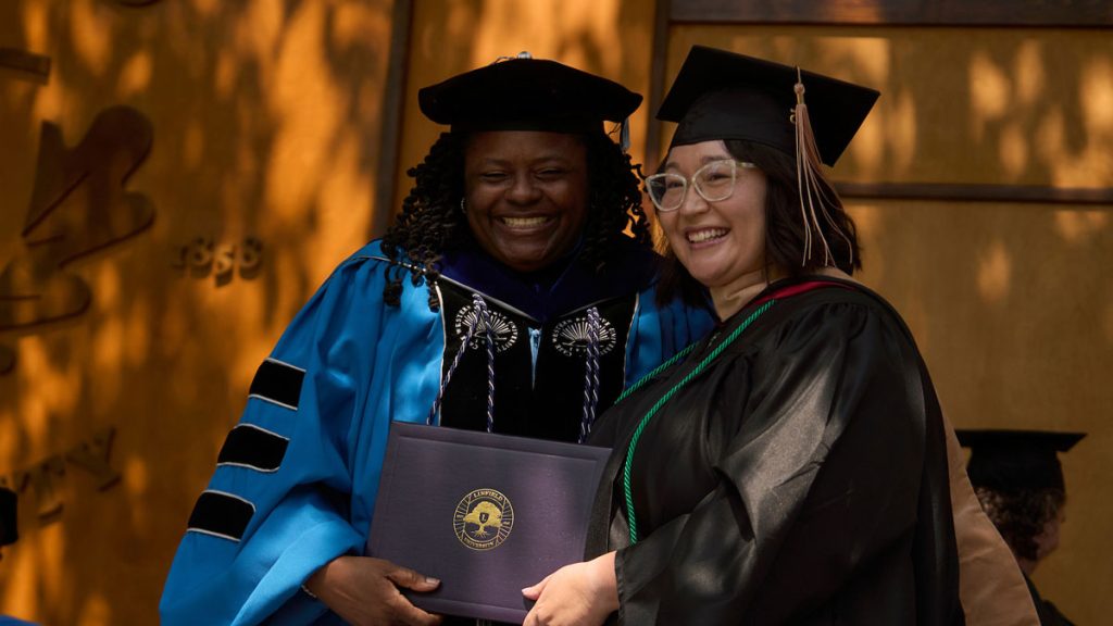 Dean Jennifer Madden poses on the Commencement stage with graduating student Azia Salbego