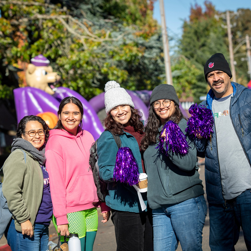 group of five family members, of different ages, pose with purple poms