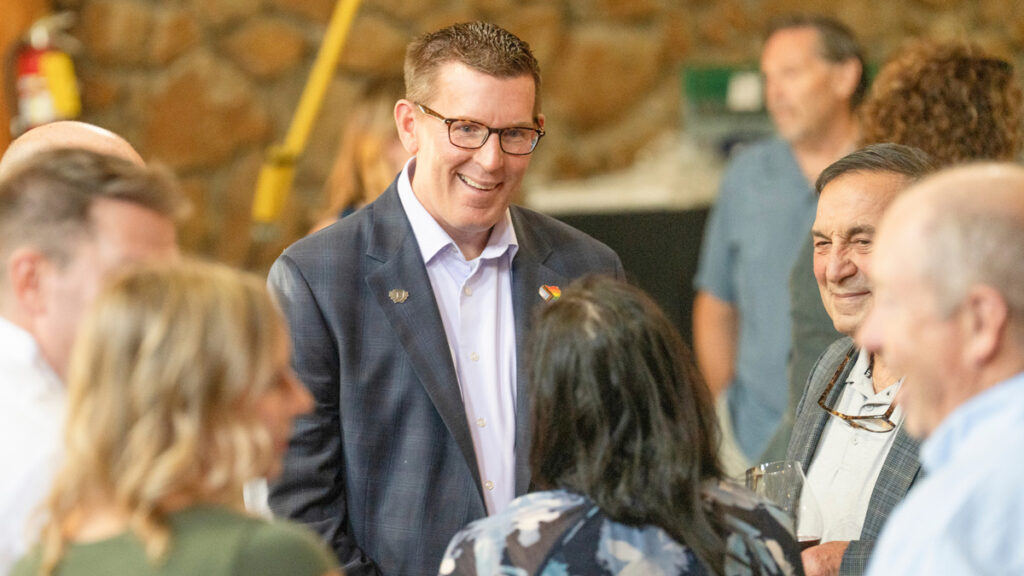 President Mark Blegen smiles and talks to a group of alumni and donors 