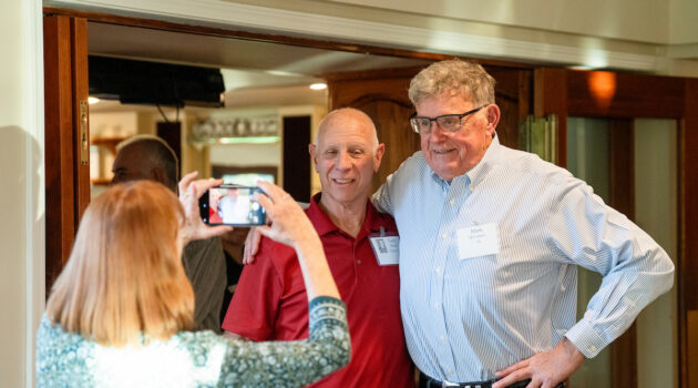 woman takes a picture of two alumni together at the Class of 1975 reunion