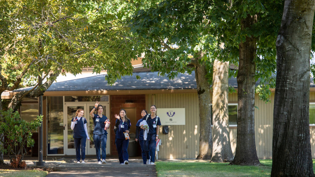 A group of nursing students walk on a sidewalk on the Portland campus