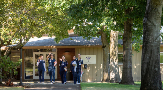A group of nursing students walk on a sidewalk on the Portland campus