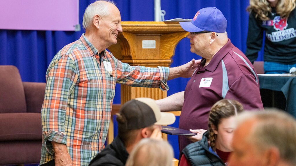Two older men give each other a hug at the BWC Tailgate.
