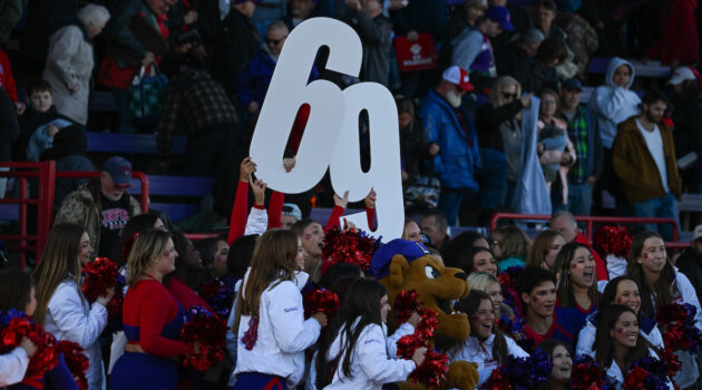 Cheerleaders hold up the numbers 69 in the football crowd