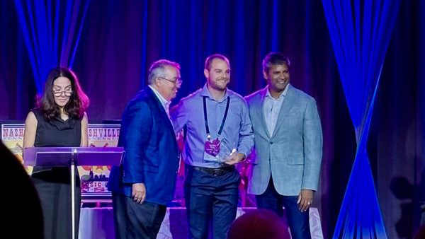 Brandon Harris is surrounded on stage with company officials as he receives his award.