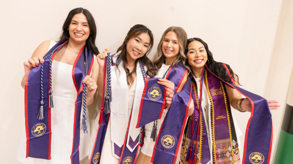 Group of four female graduates pose with their stoles.