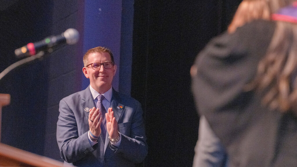 President Mark Blegen claps for nursing graduates.