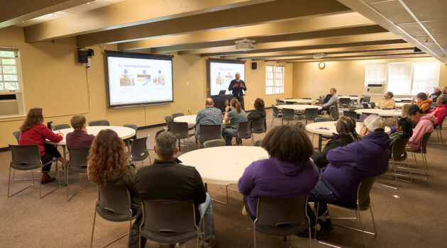 Assistant professor Enrique Washington speaks to a classroom full of people