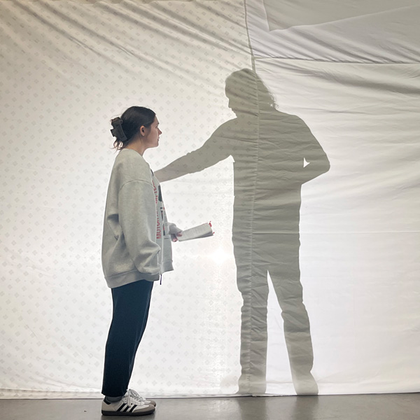 Victoria Breazeale (left) in front of a white screen. Shadow of Erik Martin seen on screen on the right.